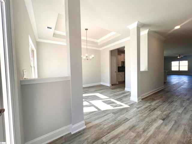 spare room featuring a notable chandelier, wood finished floors, visible vents, baseboards, and crown molding