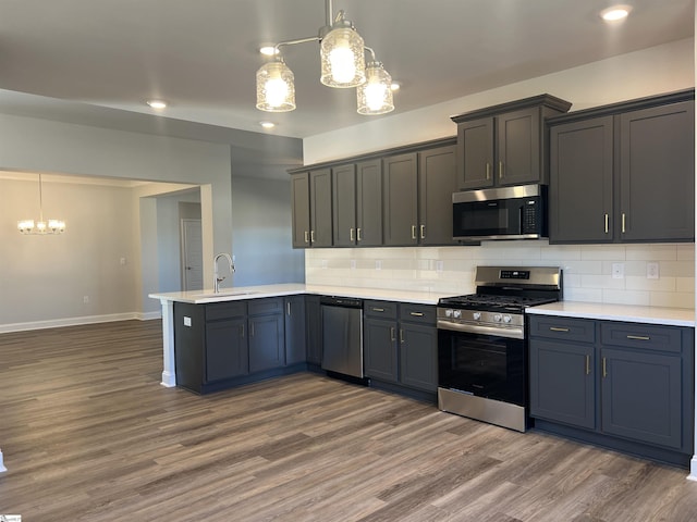 kitchen with a chandelier, kitchen peninsula, stainless steel appliances, and pendant lighting