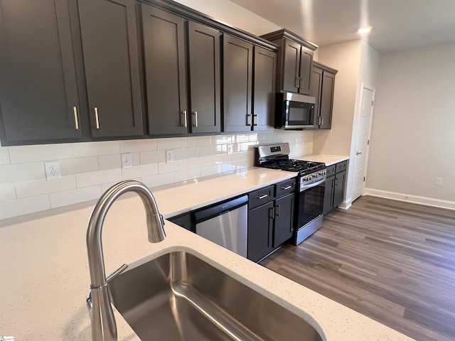 kitchen with light stone countertops, stainless steel appliances, tasteful backsplash, and sink