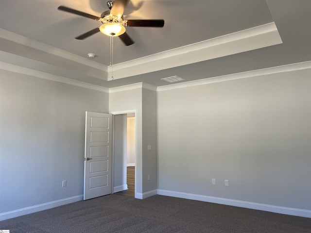 spare room with ceiling fan, crown molding, a raised ceiling, and dark carpet