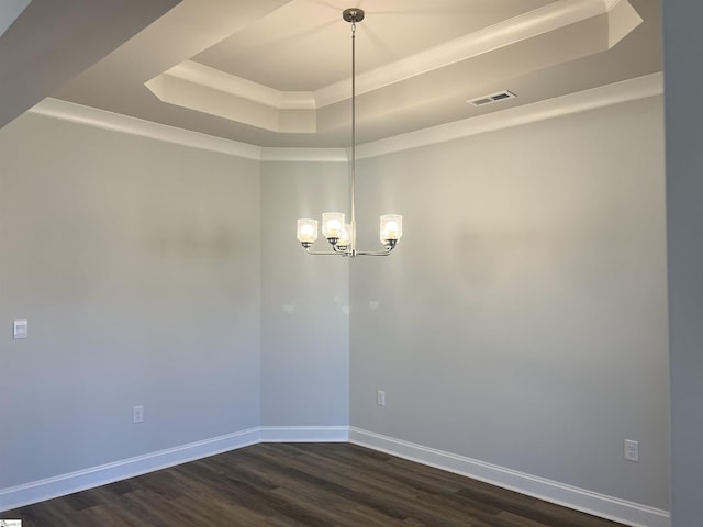 empty room with crown molding, dark hardwood / wood-style flooring, a raised ceiling, and a notable chandelier