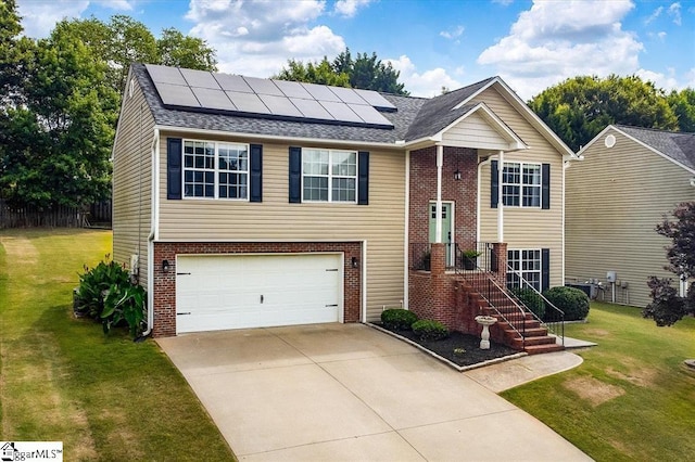 raised ranch featuring solar panels, a garage, and a front yard