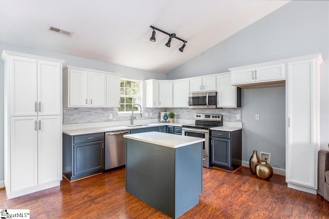 kitchen featuring vaulted ceiling, dark hardwood / wood-style floors, appliances with stainless steel finishes, a kitchen island, and white cabinetry