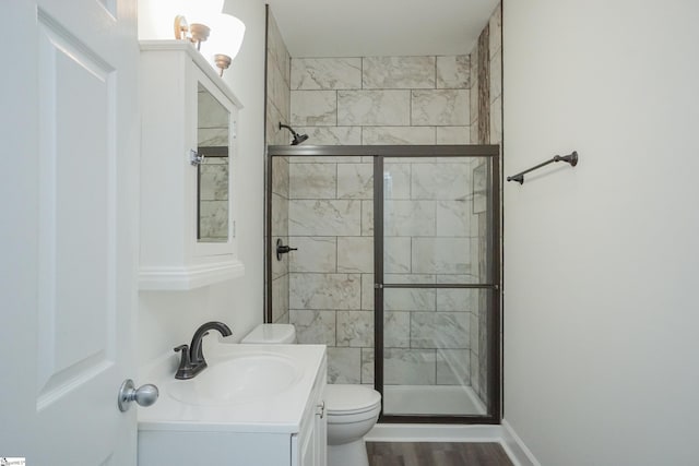 bathroom featuring hardwood / wood-style floors, vanity, a shower with door, and toilet