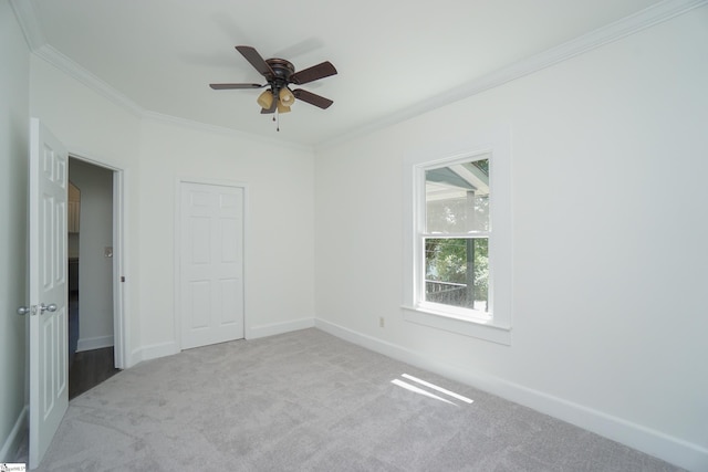 empty room featuring ceiling fan, light colored carpet, and ornamental molding