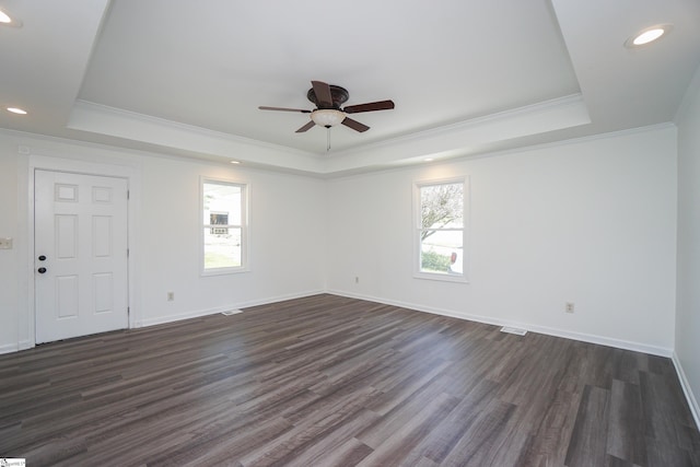 empty room with a tray ceiling, crown molding, ceiling fan, and dark hardwood / wood-style floors