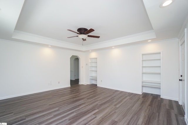 interior space featuring a tray ceiling, dark wood-type flooring, and ornamental molding