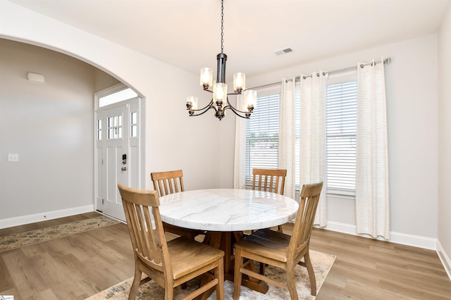 dining area with an inviting chandelier and light hardwood / wood-style floors