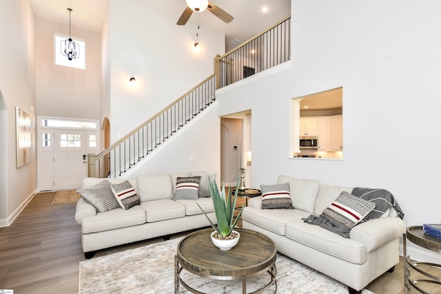 living room with ceiling fan, a towering ceiling, and hardwood / wood-style flooring