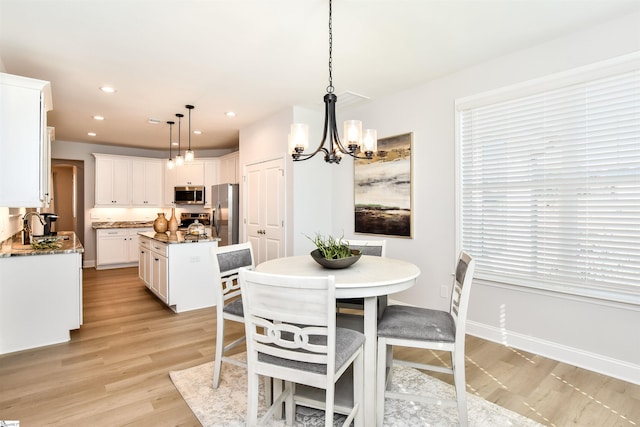 dining room with sink, a chandelier, and light hardwood / wood-style flooring