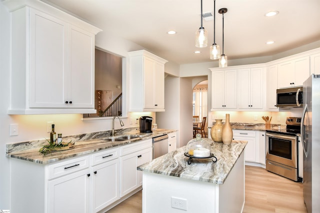 kitchen featuring a center island, white cabinetry, light wood-type flooring, stainless steel appliances, and sink