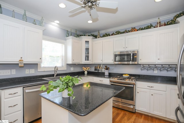 kitchen with a center island, white cabinetry, stainless steel appliances, and ornamental molding