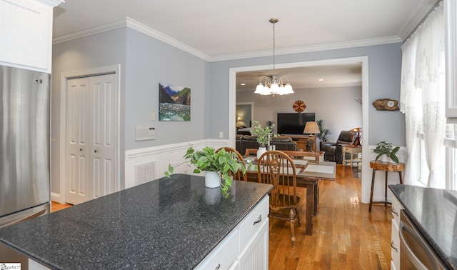 kitchen with a notable chandelier, light wood-type flooring, appliances with stainless steel finishes, decorative light fixtures, and white cabinetry