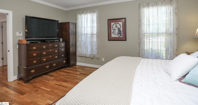 bedroom with multiple windows, crown molding, and hardwood / wood-style floors