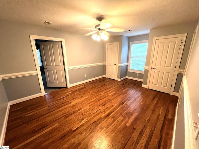 unfurnished bedroom featuring a textured ceiling, ceiling fan, and dark wood-type flooring