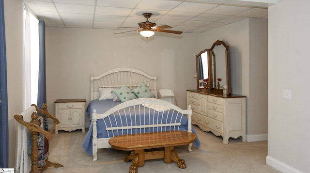 bedroom with ceiling fan, a drop ceiling, and light colored carpet