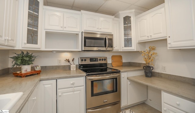 kitchen featuring white cabinets, a paneled ceiling, light tile patterned flooring, and stainless steel appliances