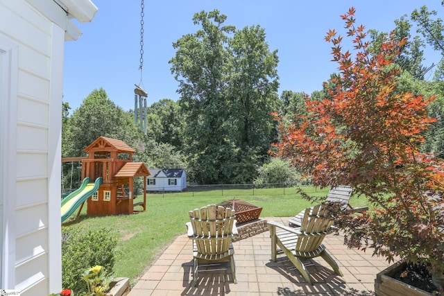 view of patio with a playground and a fire pit