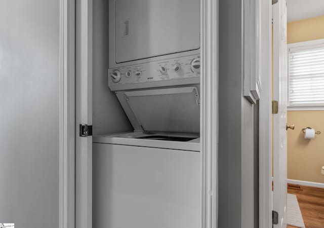 laundry area featuring hardwood / wood-style flooring and stacked washer / drying machine