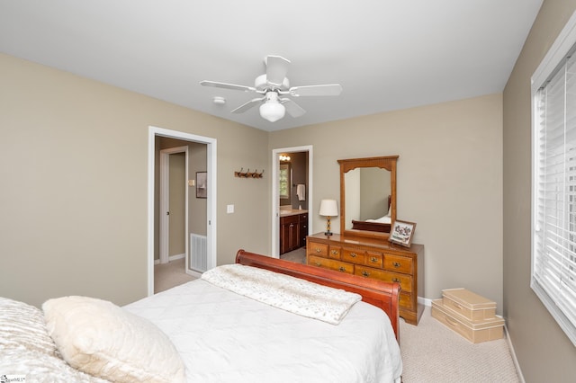 carpeted bedroom featuring multiple windows, ensuite bath, and ceiling fan