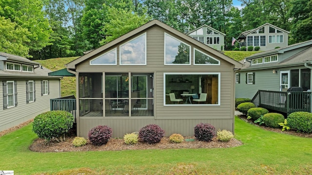 rear view of house with a sunroom and a yard