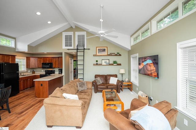 living room with beam ceiling, ceiling fan, sink, high vaulted ceiling, and light wood-type flooring