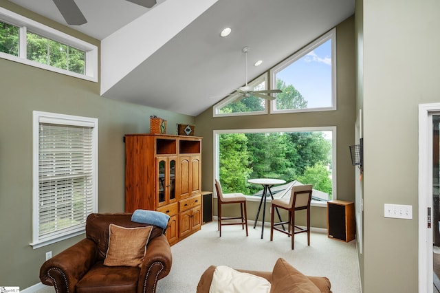 sitting room with ceiling fan, a healthy amount of sunlight, light carpet, and high vaulted ceiling