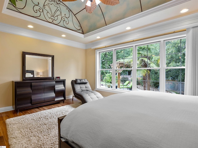 bedroom with hardwood / wood-style flooring, a raised ceiling, ceiling fan, and crown molding