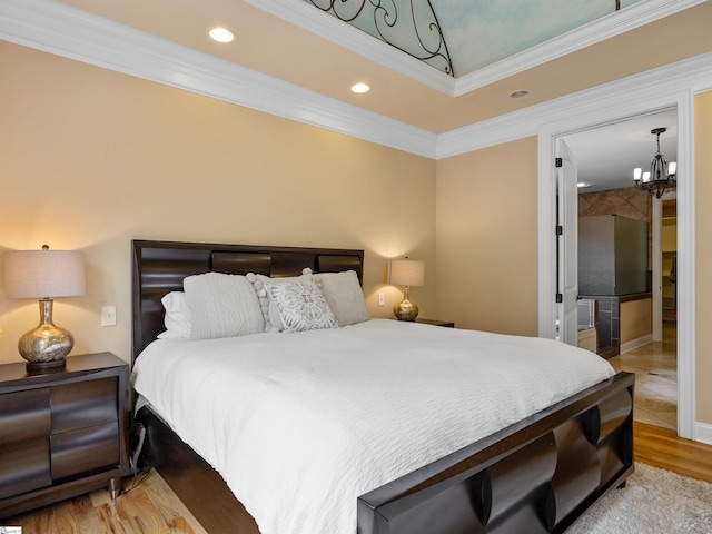 bedroom featuring a chandelier, ensuite bath, crown molding, and light hardwood / wood-style flooring