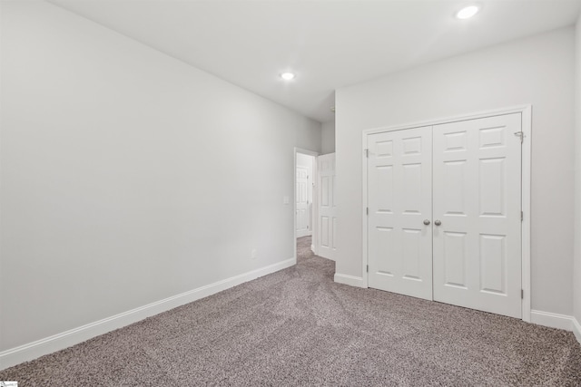 unfurnished bedroom with a closet, recessed lighting, baseboards, and carpet