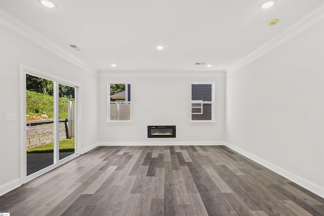 unfurnished living room with wood finished floors, baseboards, a glass covered fireplace, and crown molding