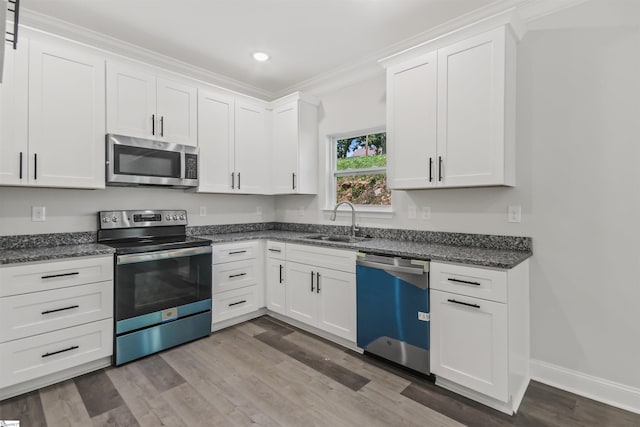 kitchen featuring hardwood / wood-style flooring, ornamental molding, white cabinets, sink, and appliances with stainless steel finishes