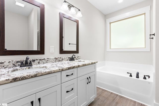 bathroom featuring hardwood / wood-style floors, a washtub, and vanity