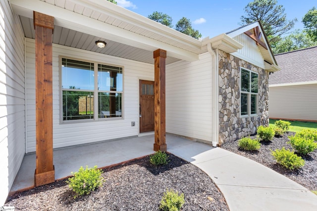 entrance to property featuring a porch and stone siding