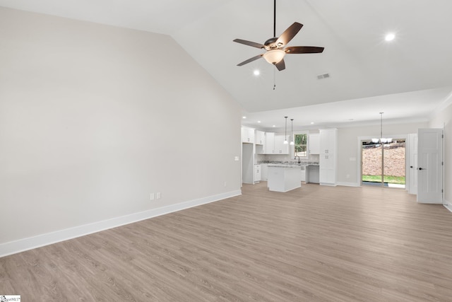 unfurnished living room with ceiling fan with notable chandelier, light hardwood / wood-style flooring, and lofted ceiling