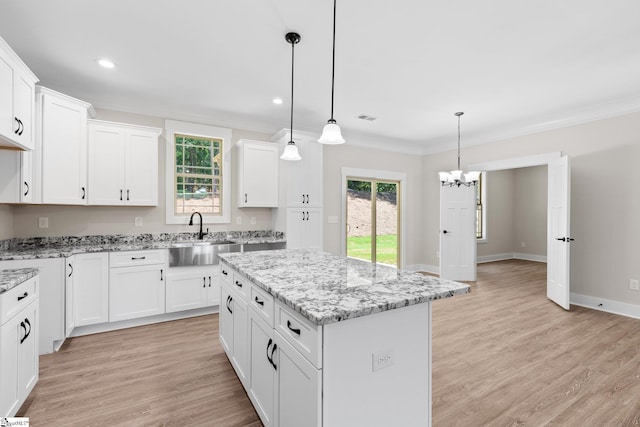 kitchen with white cabinets, a kitchen island, light wood-type flooring, and pendant lighting