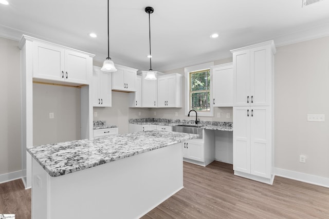 kitchen with light stone countertops, a center island, white cabinetry, and hanging light fixtures