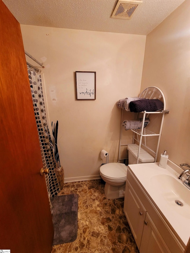 bathroom featuring a shower with curtain, vanity, toilet, and a textured ceiling