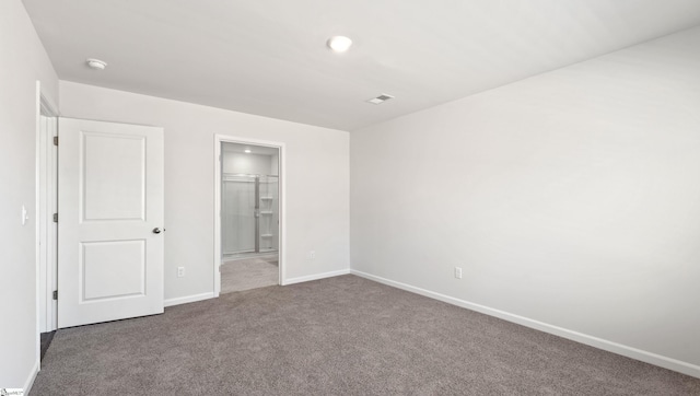 unfurnished bedroom with dark carpet and ensuite bath