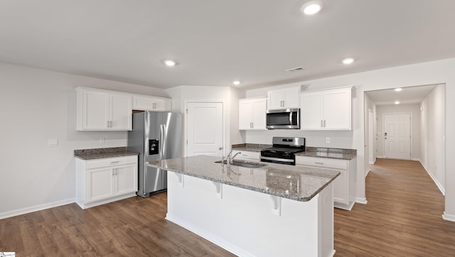 kitchen with sink, white cabinetry, stainless steel appliances, a kitchen breakfast bar, and a center island with sink