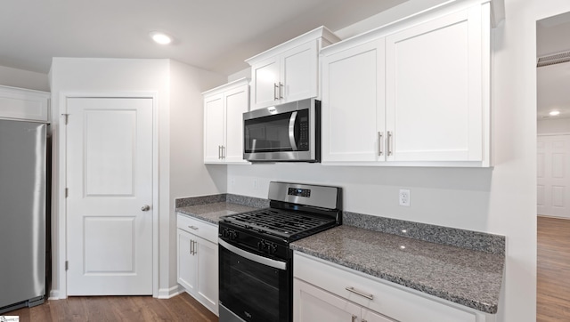 kitchen featuring white cabinetry, stainless steel appliances, dark hardwood / wood-style floors, and dark stone counters