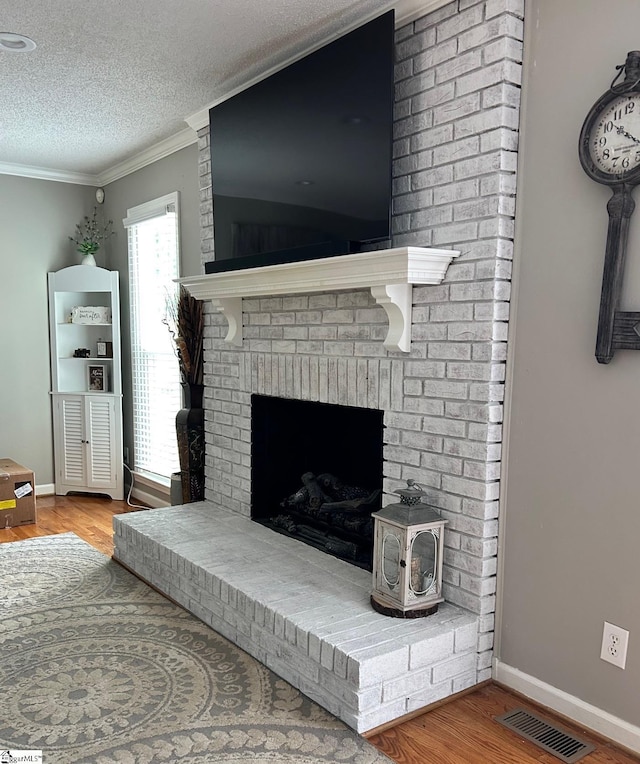 interior details with hardwood / wood-style flooring, a textured ceiling, crown molding, and a brick fireplace