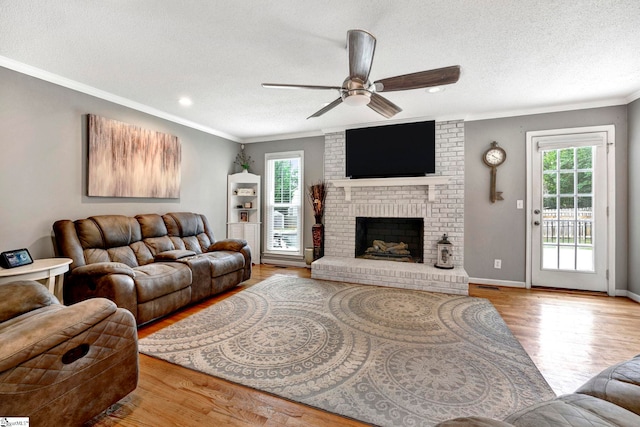 living room with a fireplace, a textured ceiling, light wood-type flooring, and ceiling fan