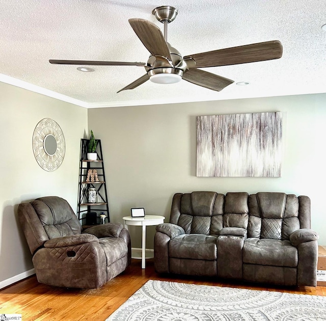 living room featuring hardwood / wood-style floors, ceiling fan, crown molding, and a textured ceiling