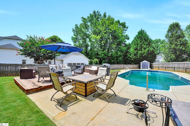 view of swimming pool featuring an outbuilding, a deck, an outdoor fire pit, and a grill