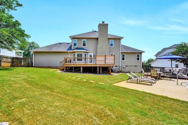 rear view of house with a lawn, a wooden deck, and a patio