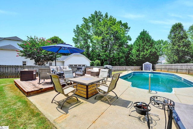 view of pool featuring a grill, a wooden deck, an outdoor living space with a fire pit, and a storage unit