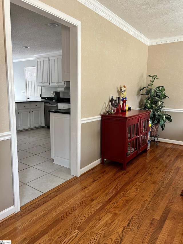 hallway featuring tile patterned flooring, a textured ceiling, and crown molding