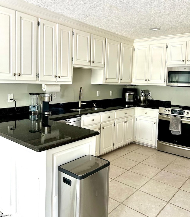 kitchen featuring kitchen peninsula, appliances with stainless steel finishes, sink, light tile patterned floors, and white cabinetry