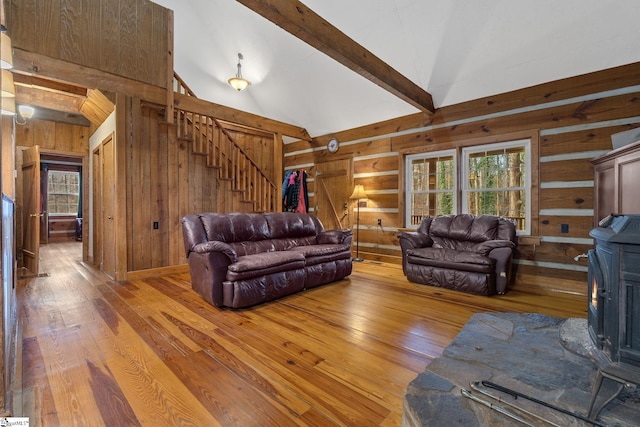 living room with wood walls, light wood-type flooring, beam ceiling, and high vaulted ceiling